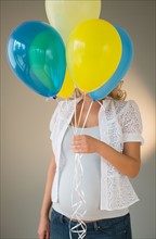 Pregnant woman holding bunch of balloons