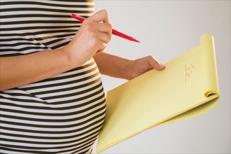 Pregnant woman holding pencil and notebook