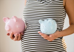 Pregnant woman holding piggy banks