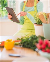 Teenage girl using digital tablet in kitchen