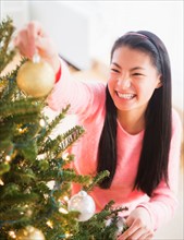 Teenage girl ( 16-17 years) decorating Christmas tree