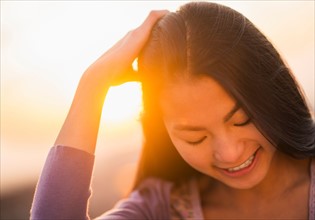 Close-up of smiling teenage girl ( 16-17 years) with sunset in background