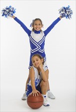 Portrait of cheerleaders (8-9 years) ( 10-11 years) holding pom-pom and ball
