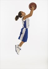 Side view of girl (8-9 years) playing basketball