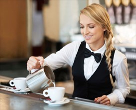 Female barista pouring milk into coffee cup