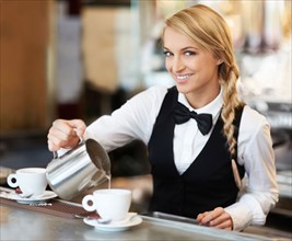 Female barista pouring milk into coffee cup