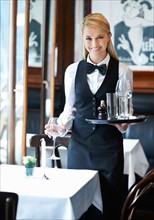 Portrait of young waitress holding tray and wine glasses