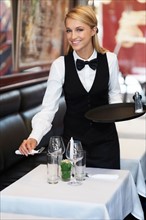 Portrait of young waitress setting table