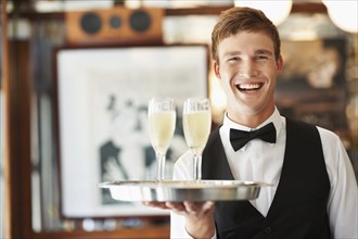 Portrait of waiter holding champagne flutes on tray