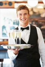 Portrait of waiter holding champagne flutes on tray