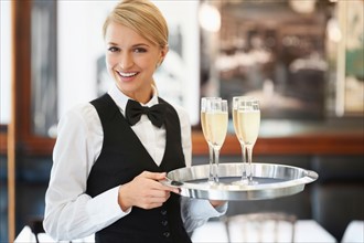 Portrait of waitress holding champagne flutes on tray