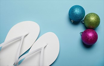 Christmas decorations and pair of flip-flops on blue background