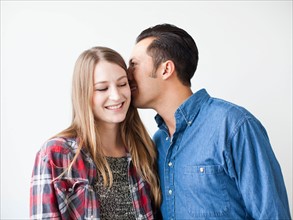 Studio Shot portrait of young couple whispering and smiling
