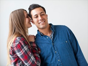 Studio Shot portrait of young couple whispering and smiling