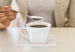 Close-up of woman sweetening coffee.