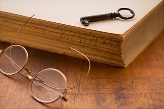 Antique book with key and eyeglasses.