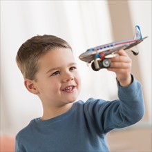 Boy (4-5) playing with toy plane.