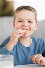 Boy (4-5) eating cookie.
