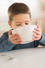 Boy (4-5) drinking from bowl.