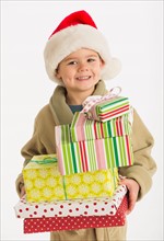 Portrait of boy (4-5) carrying christmas presents.