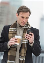 Man in winter clothes looking at phone.