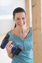 Portrait of woman using hand drill.