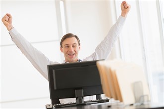 Office worker cheering in front of computer.