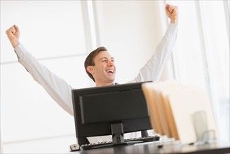 Office worker cheering in front of computer.