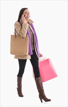 Woman carrying shopping bags and talking on phone.