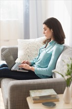 Woman sitting on sofa and using laptop.