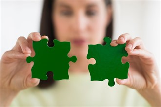 Woman holding green puzzle pieces.