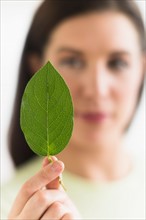 Woman holding green leaf.