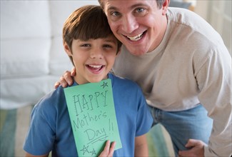 Father and son (8-9) holding Mother's day card