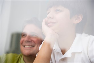 Son (8-9) and father looking through window