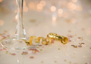 Champagne flute on table decorated with confetti and streamer