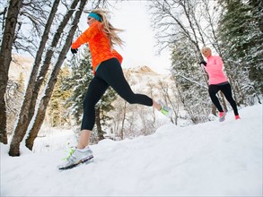 Two women jogging in winter forest
