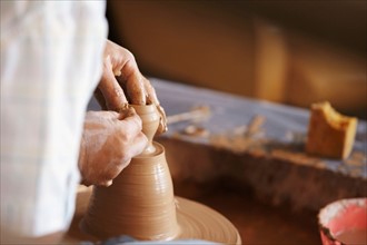 Hands working with clay on potter's wheel