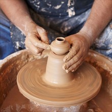 Elevated view of hands working with clay on potter's wheel
