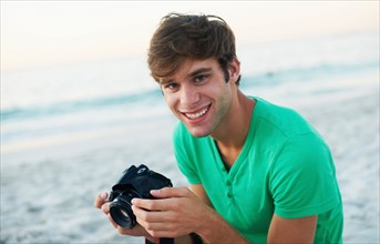 Portrait of young man taking pictures at beach
