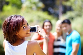Portrait of young woman taking photo of people