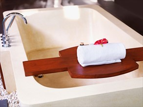Bathtub with towel on wooden shelf