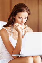 Woman using laptop while sitting on bed