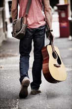 Man with guitar walking down street