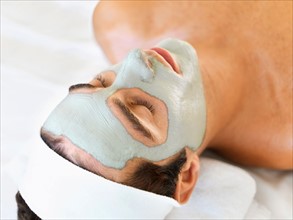 Man with face mask relaxing in spa