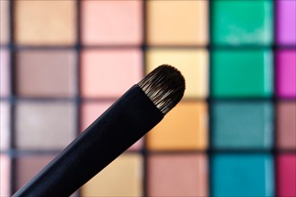 Make-up brush against eye shadow palette, studio shot