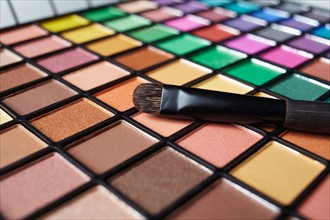 Make-up brush on eye shadow palette, studio shot