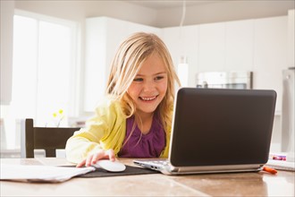 Blonde girl (6-7) using laptop