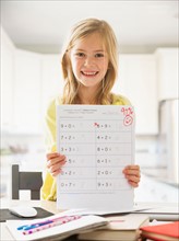 Proud girl (6-7) showing math test
