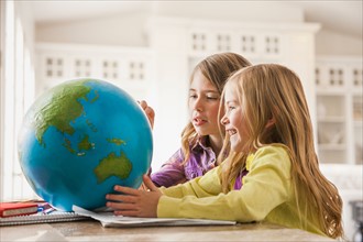 Two girls (6-7) doing homework with globe