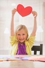 Girl (6-7) holding red paper heart